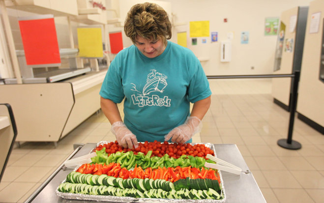 Carrie Anderson, a lead food services employee with the South Milwaukee School District, works on setting up a vegetable tray being served as part of the free lunch program. New standards take effect July 1 for schools participating in the National School Lunch Program. - Image credit: Mike De Sisti