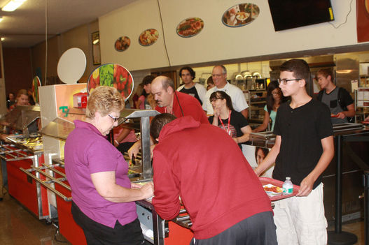 Jeff Smith/Star-Herald.- Jan Cortinas, head baker at Scottsbluff High School, helps Elijah Salinas with the payment of his lunch. Nate Blackos patiently waits as other students and teachers line up in the cafeteria.