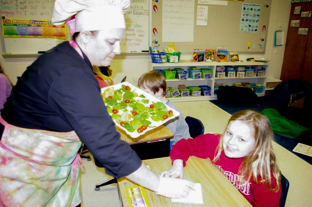 Taher chef Irene Pawlisch hands out a healthy snack to Wilson Elementary third grader Andrea Riesen on Thursday during a presentation about healthy eating at the school