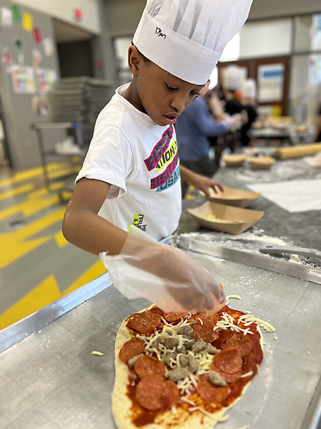 Ducombe 3rd grader Tyson Johnson making pizza